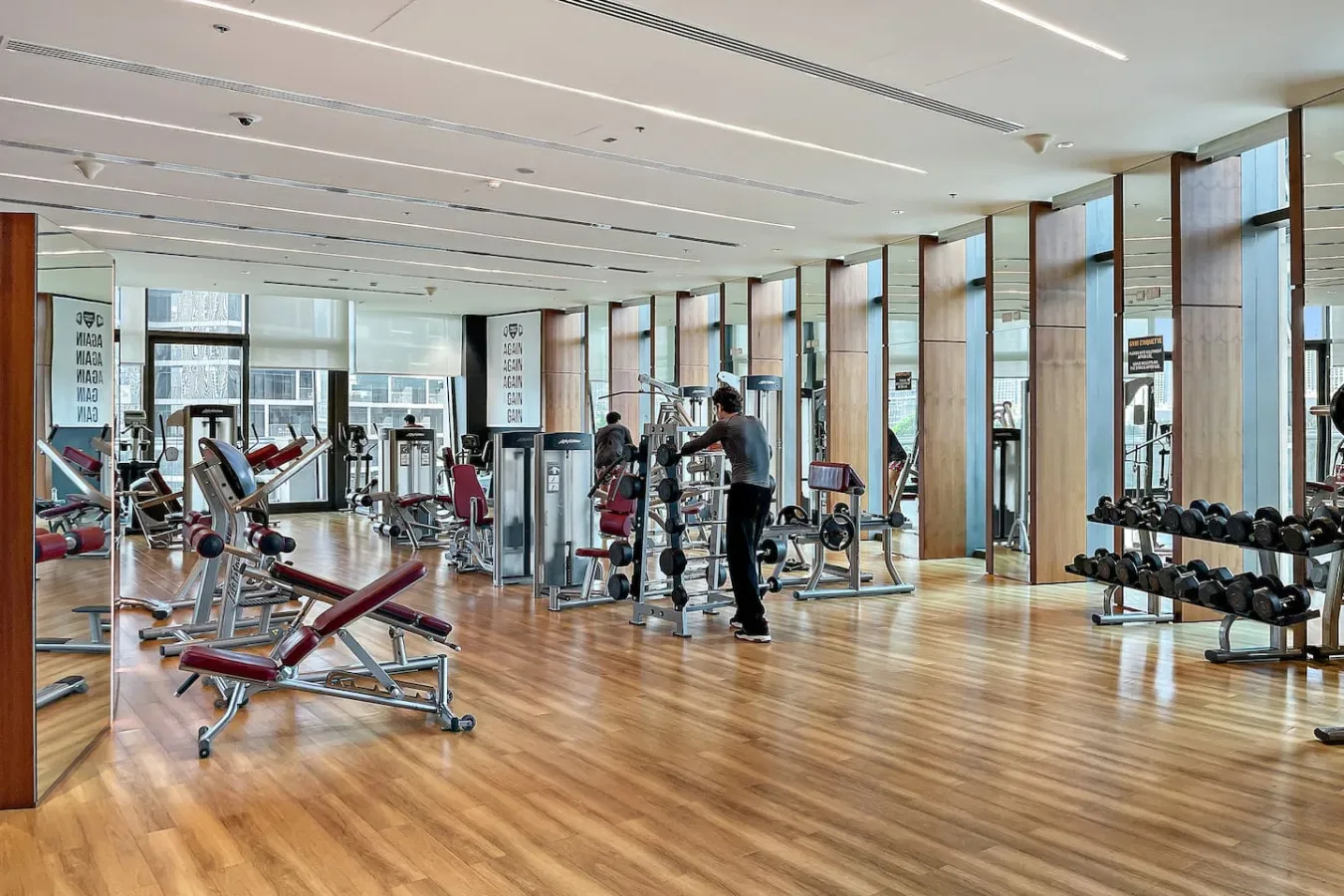 A gym with weight machines, free weights, and mirrored walls.