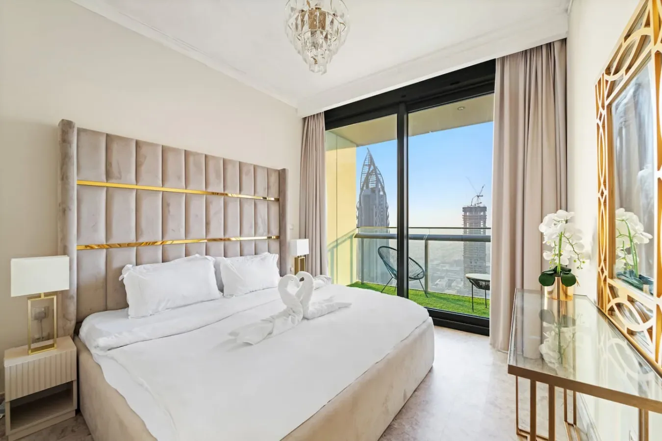 A bright bedroom with a large bed beside floor-to-ceiling windows.