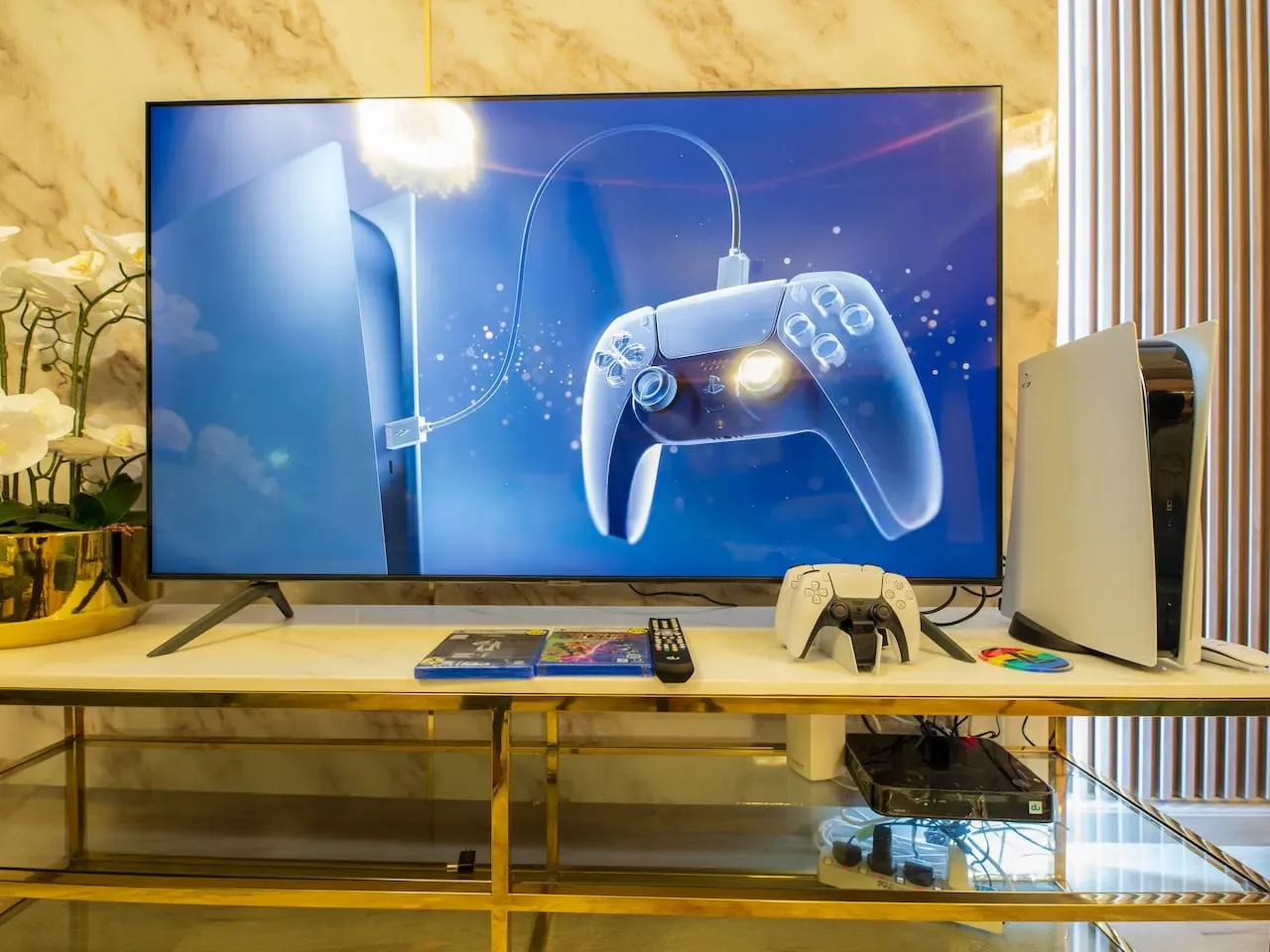 A television and video game consoles sit on a gold-framed media table.