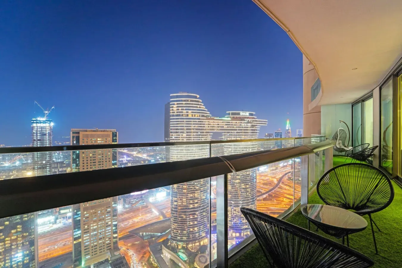 A balcony overlooks illuminated city buildings at night.