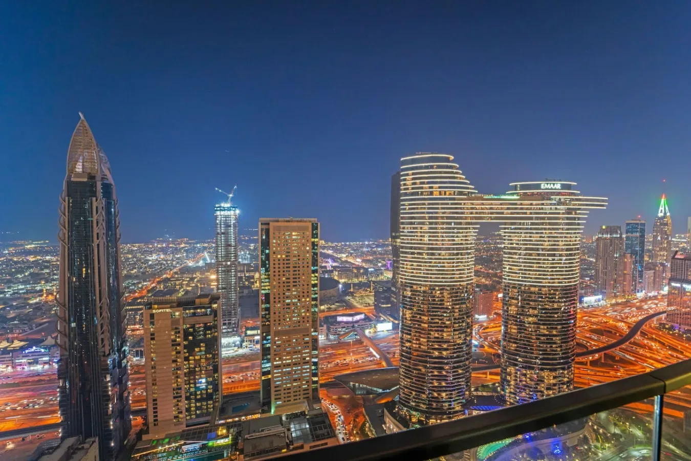 A nighttime city skyline with illuminated high-rise buildings and roads.