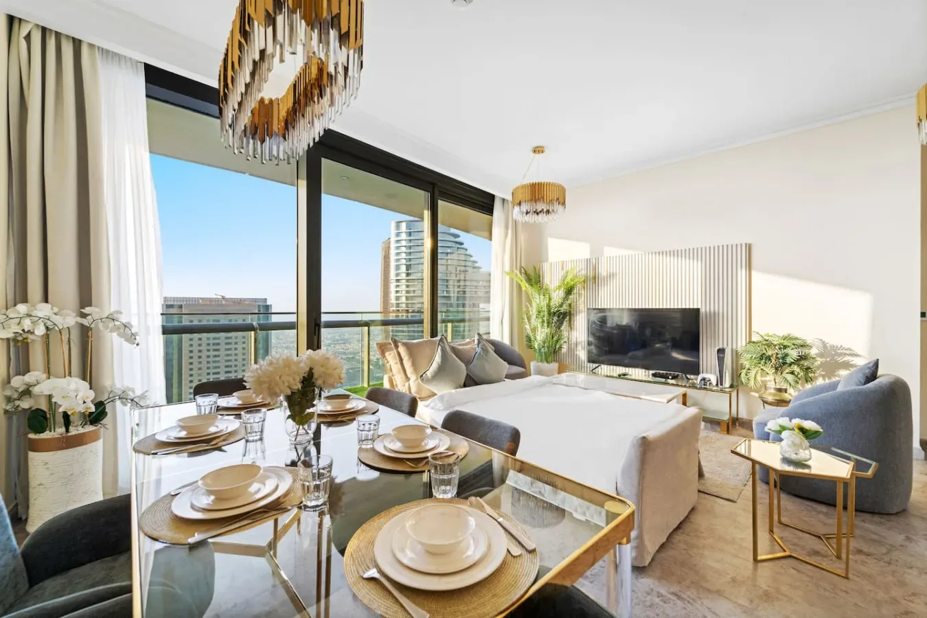 A bright living and dining area with large windows, seating, and a set dining table.