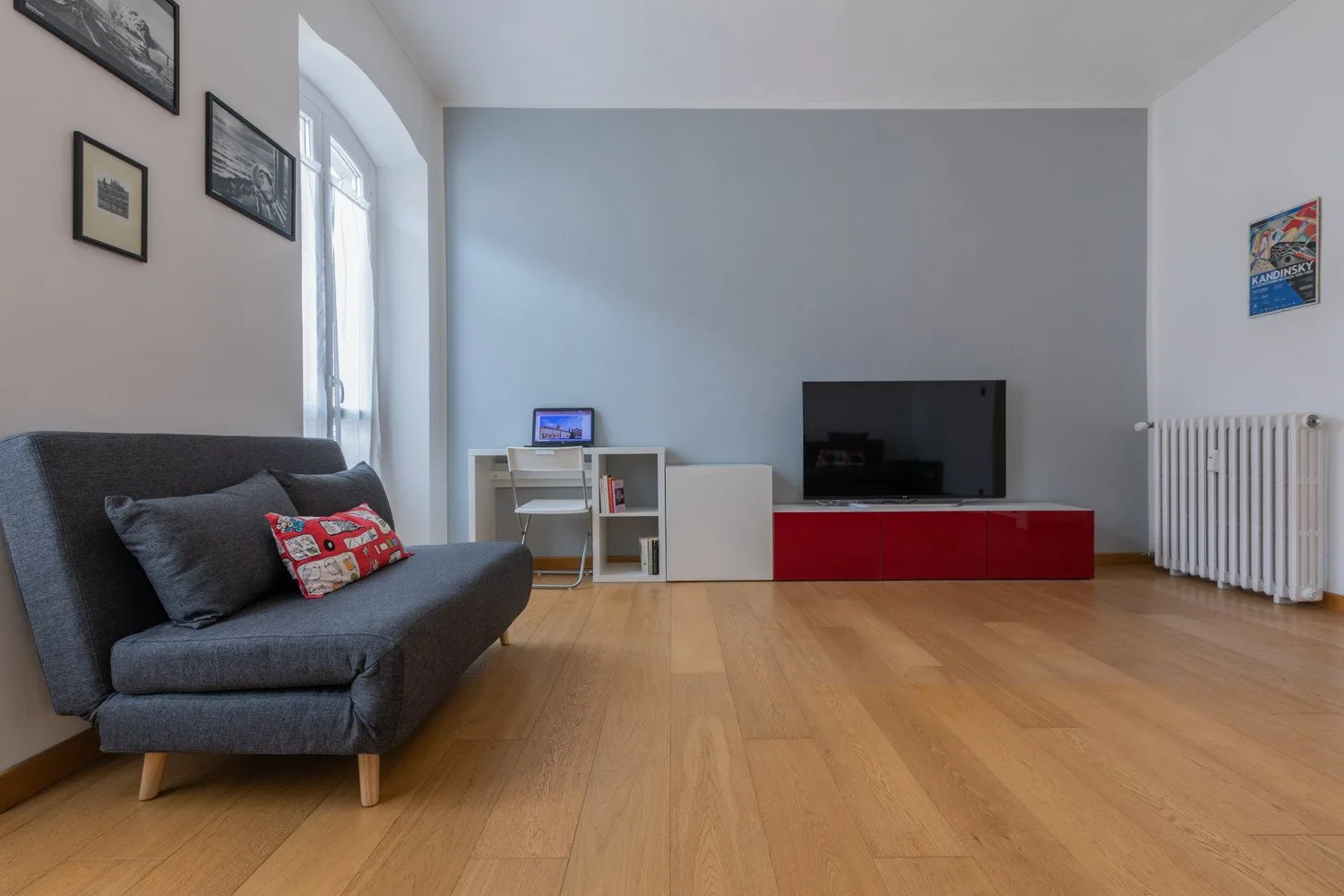 Una sala de estar con asientos, un televisor y suelo de madera.