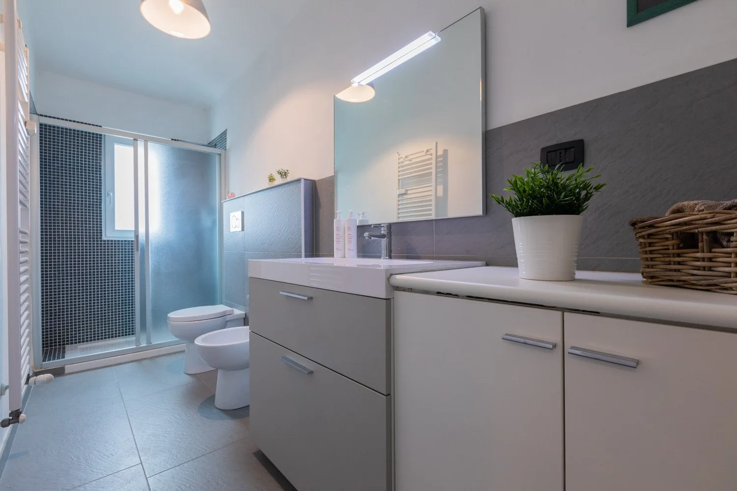 Un baño con ducha de vidrio, inodoro y lavabo con mueble.