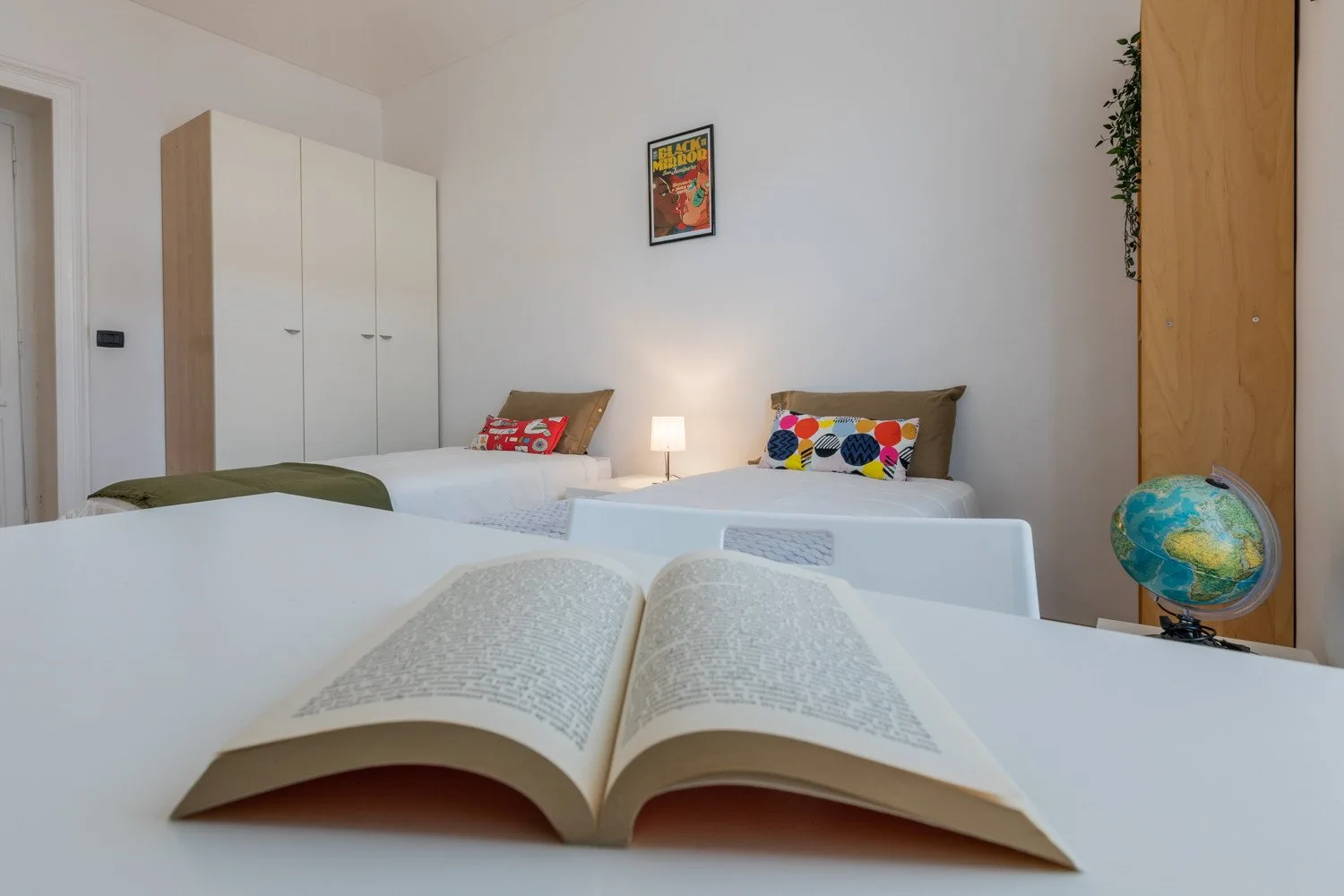 Dormitorio con dos camas y un libro abierto en primer plano.
