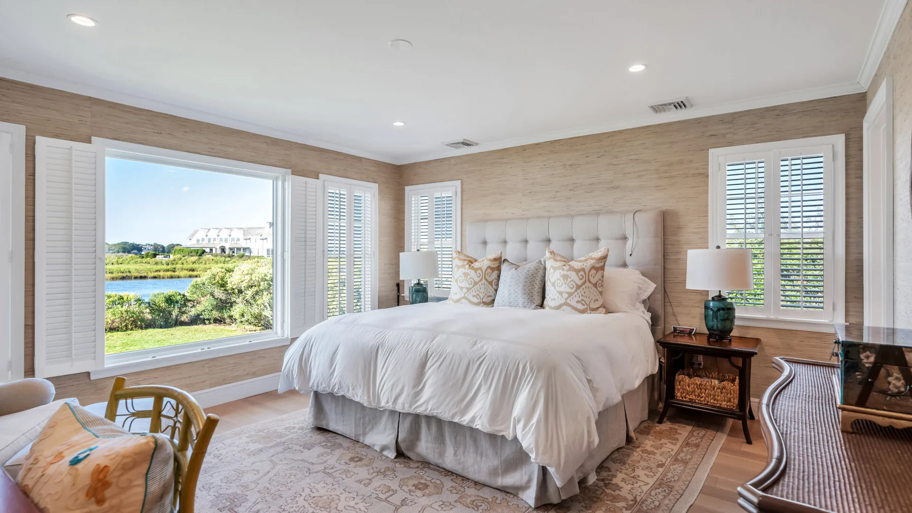 Un dormitorio luminoso con una cama grande y ventanas con vistas a la vegetación.