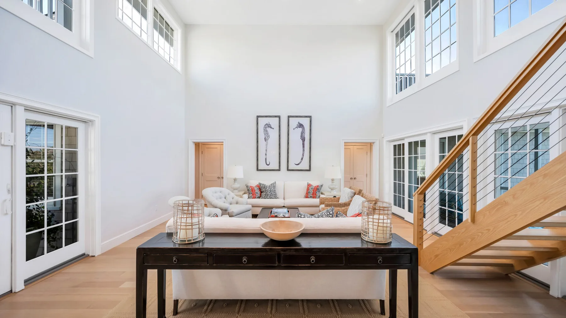 Una sala luminosa con sofá, mesa de centro y escalera.