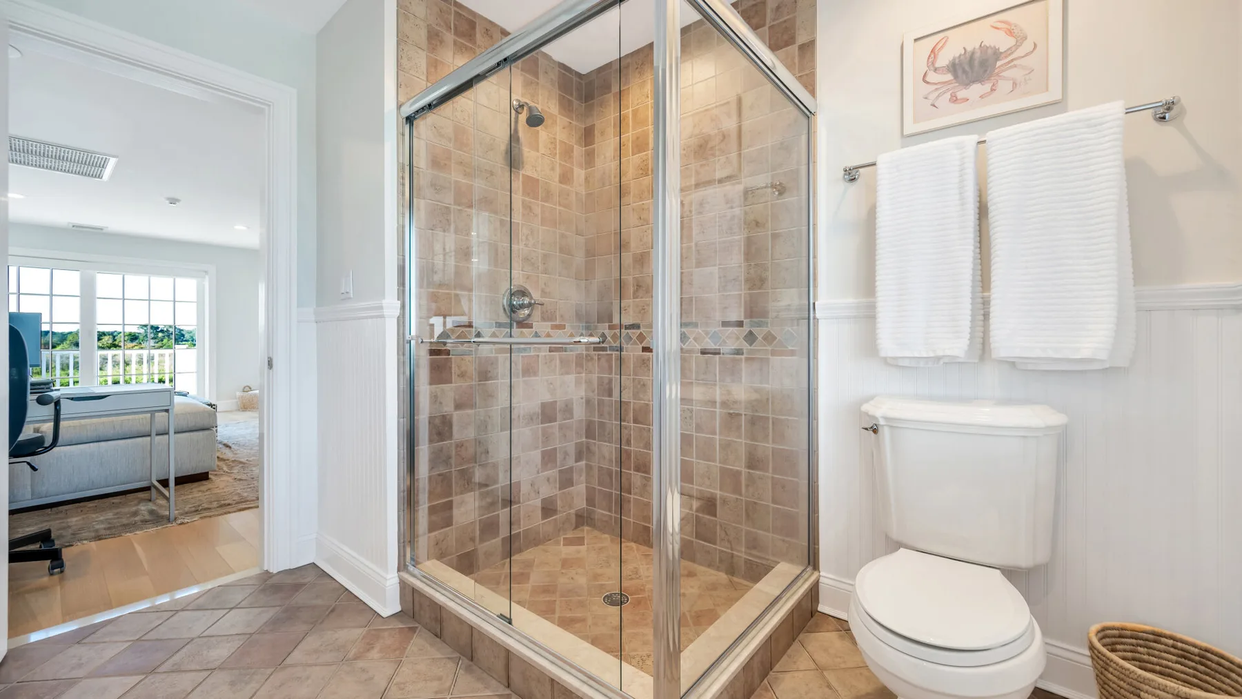Un baño con una ducha de vidrio y un inodoro junto a una puerta abierta.