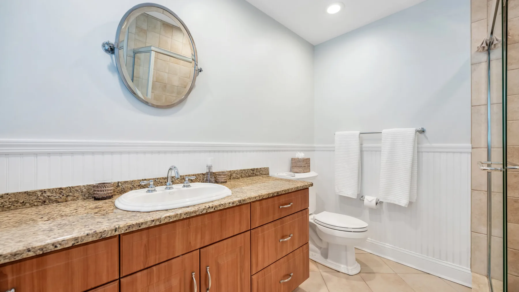 Un baño con un mueble largo, lavabo y toallas junto a la ducha.