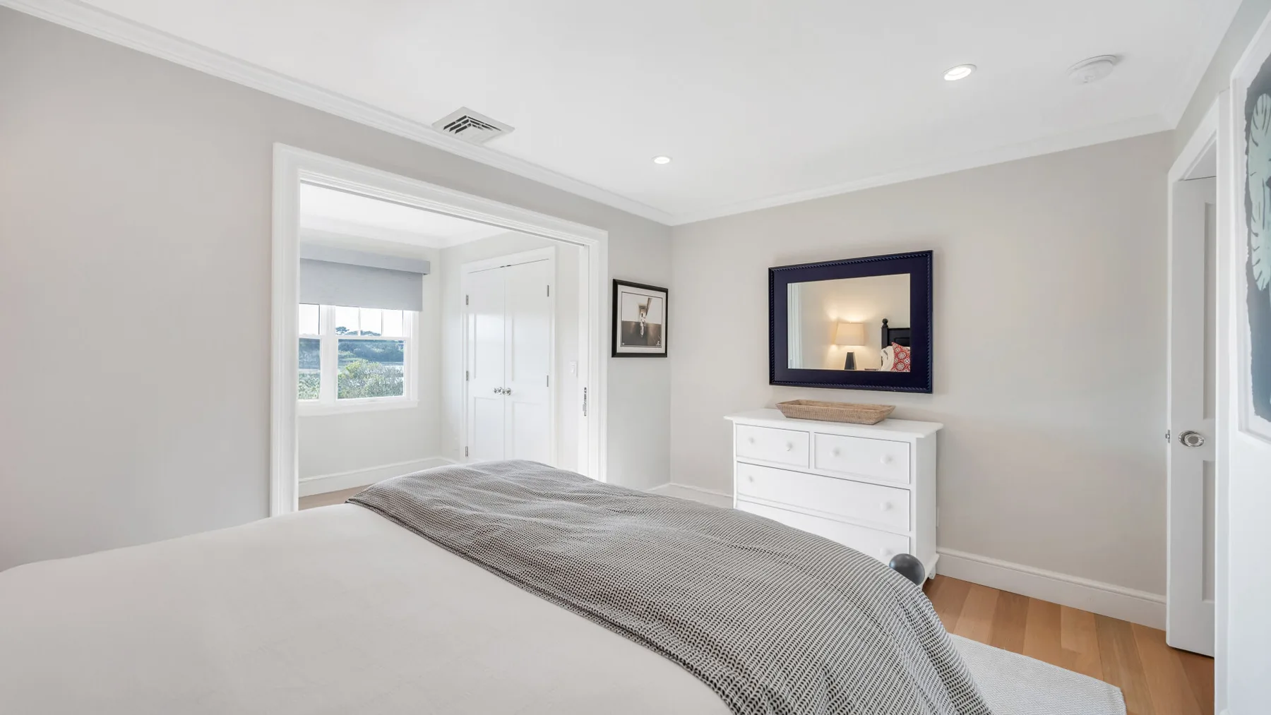 Un dormitorio luminoso con una cama, una cómoda y una ventana.