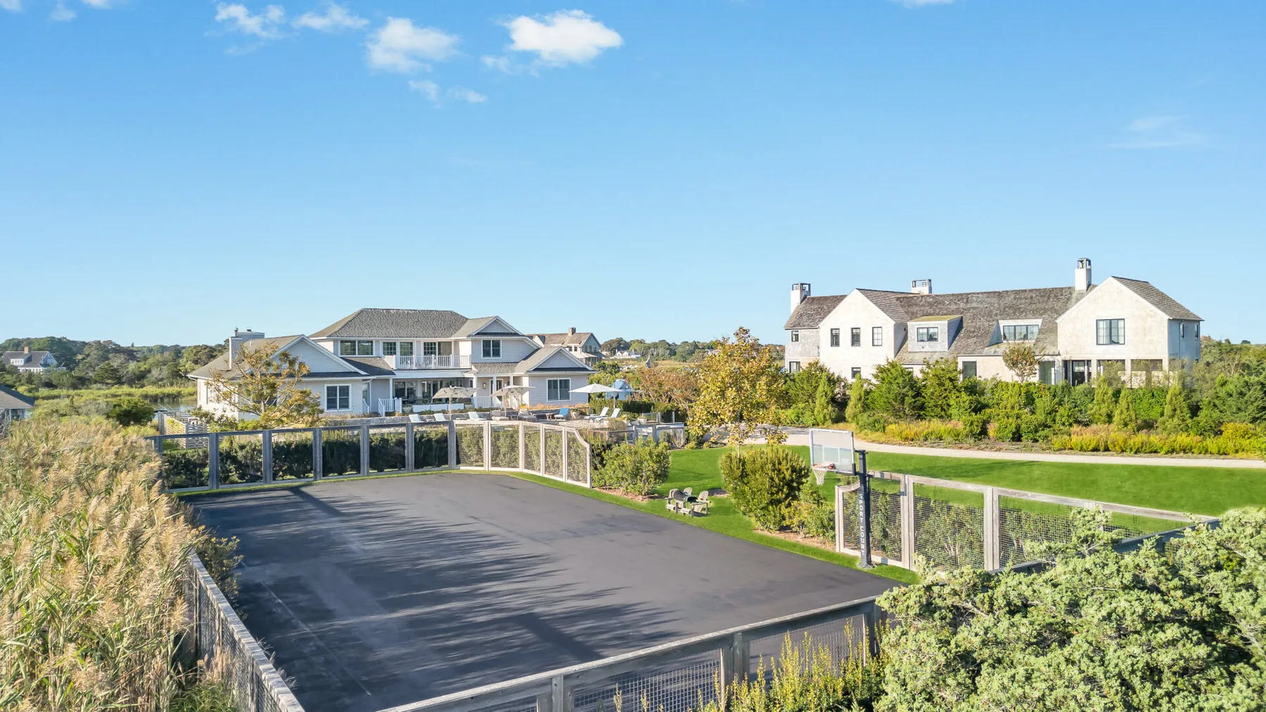 Un área exterior pavimentada con barandillas bajas, vegetación y casas cercanas.