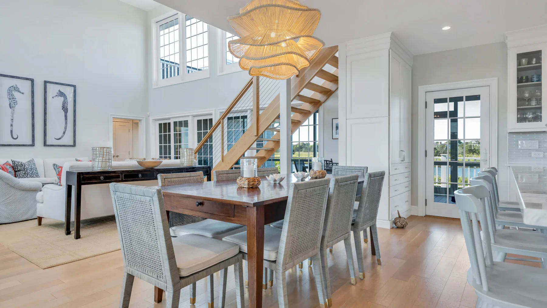 Un comedor luminoso con una mesa de madera bajo lámparas colgantes tejidas.