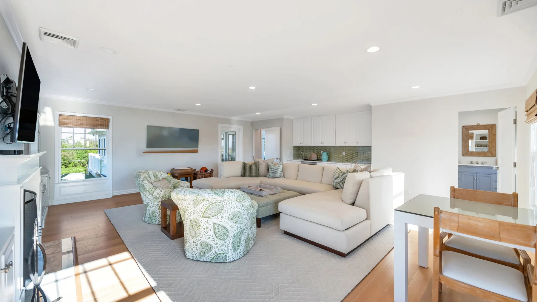 Una sala luminosa con un área de asientos en forma de L y ventanas grandes.