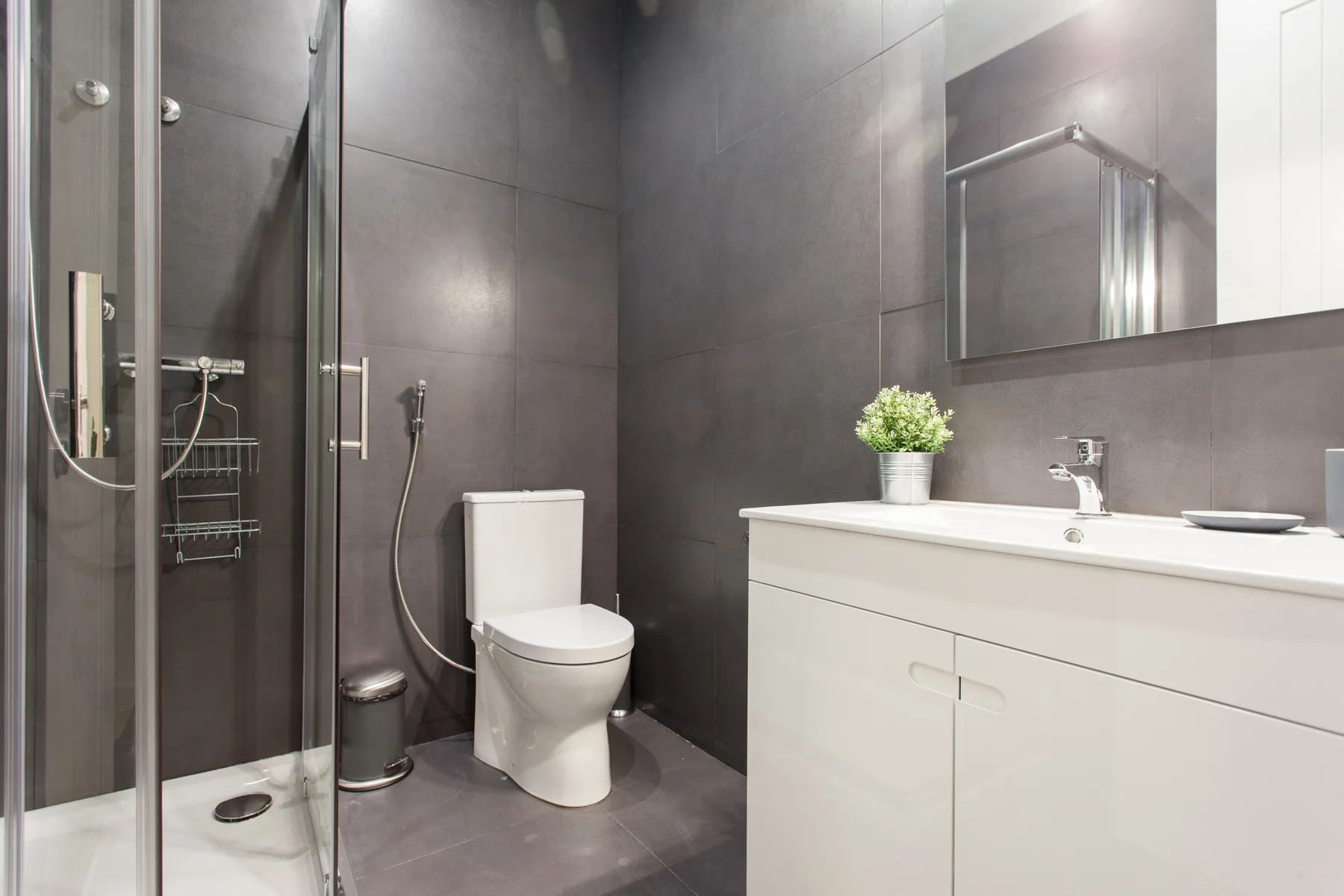Un baño moderno con ducha de cristal, inodoro y tocador blanco.