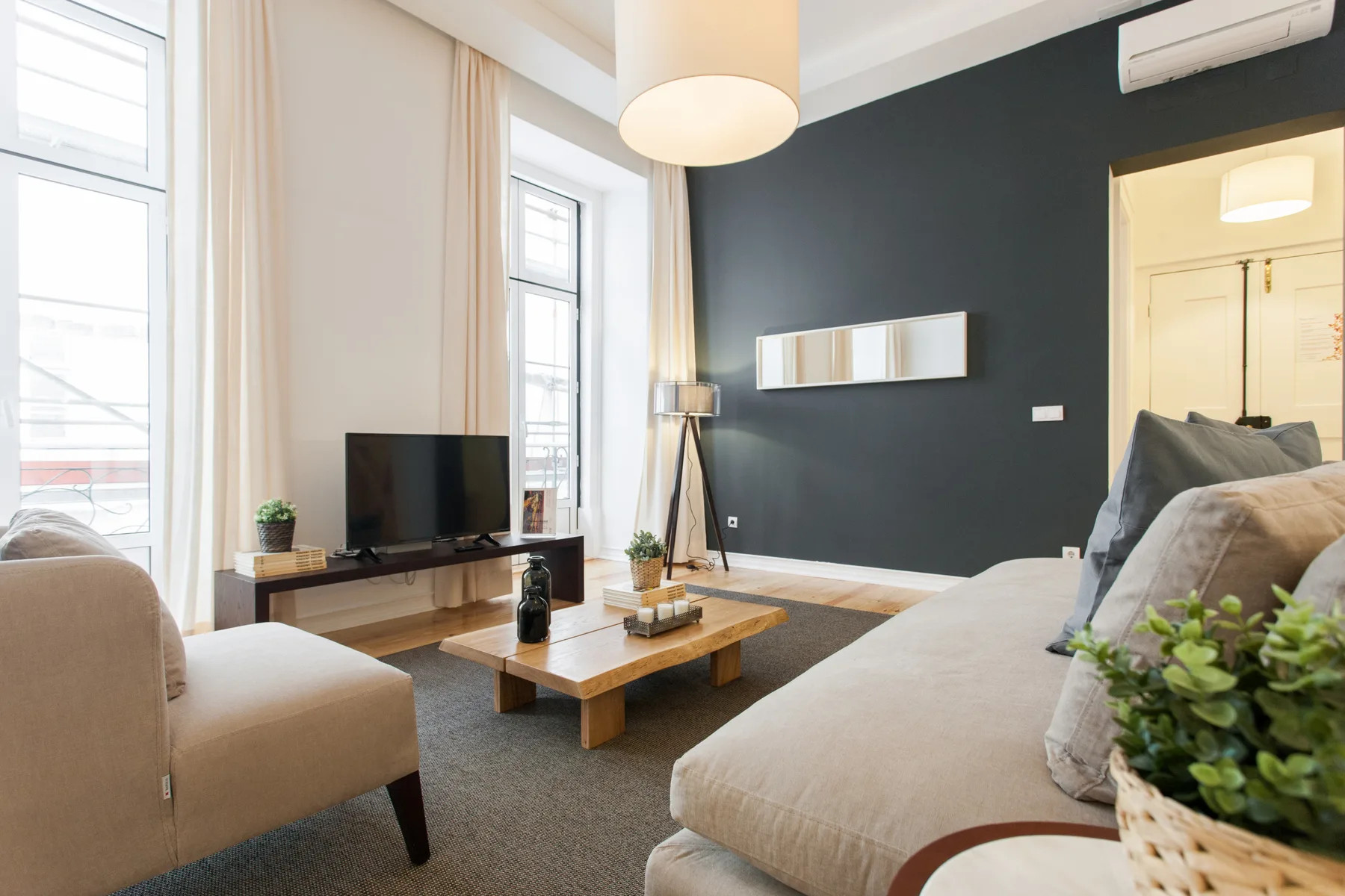 Una sala de estar luminosa con asientos, un televisor y una mesa de centro de madera.