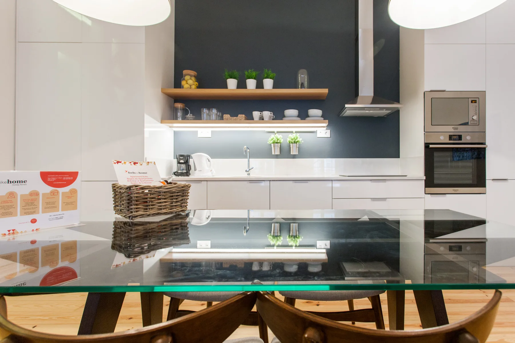 Una cocina moderna con salpicadero oscuro, encimera y mesa de comedor de vidrio.