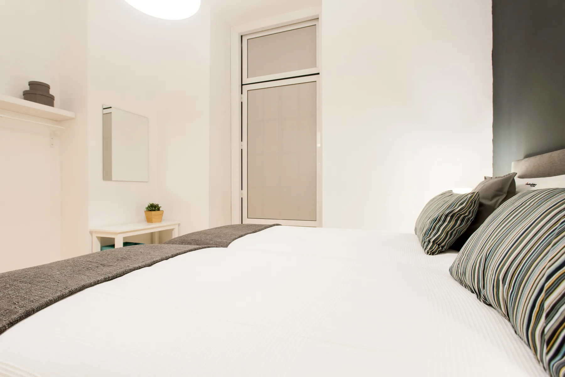 Un dormitorio luminoso con una cama bien hecha y almohadas a rayas.