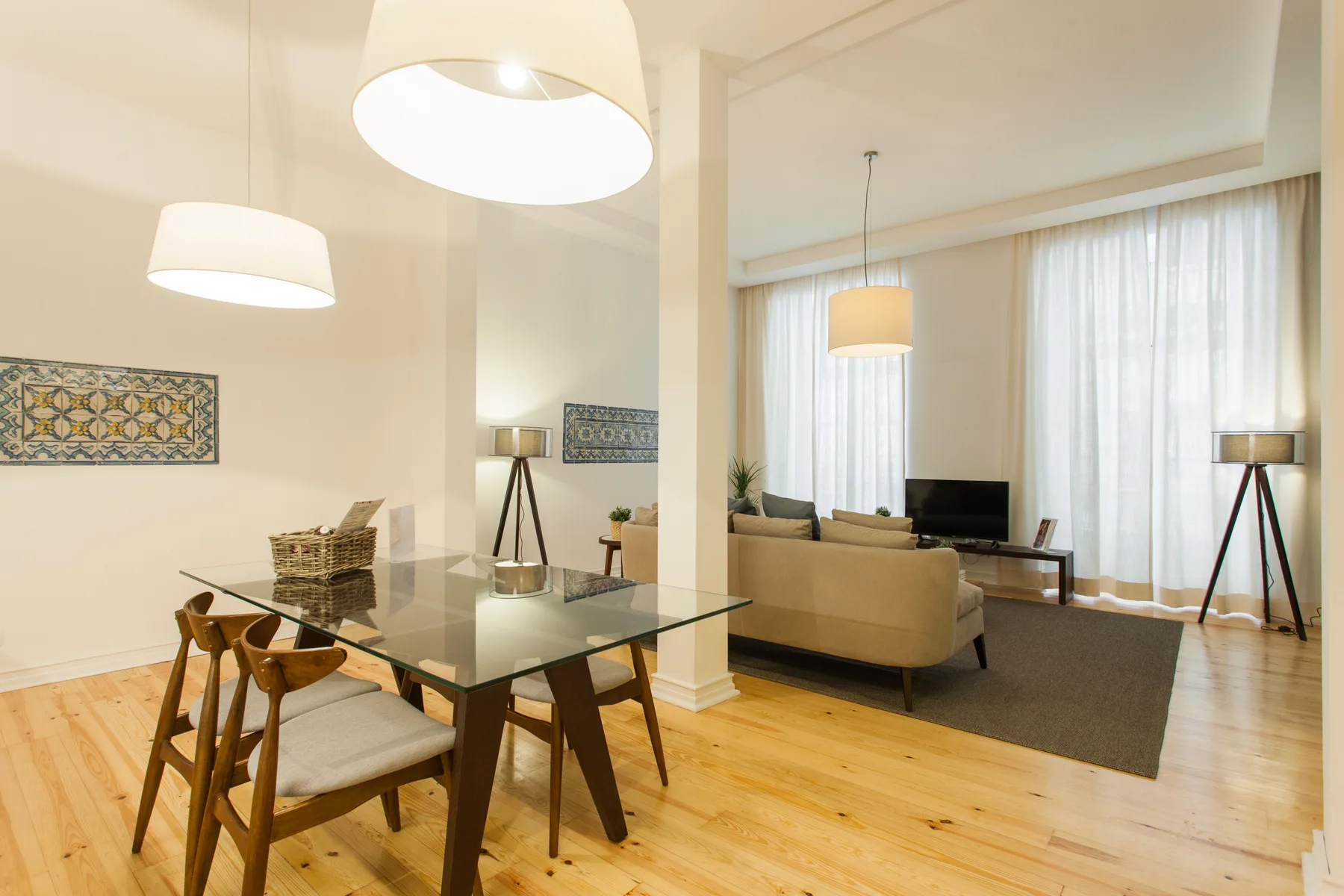 Una luminosa sala de estar y comedor con una mesa de vidrio y asientos junto a las ventanas.