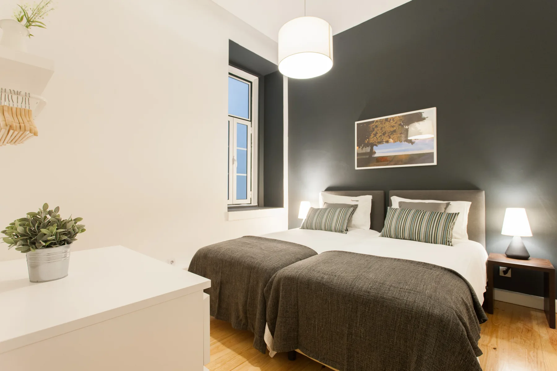 Un dormitorio con dos camas, mesitas de noche y un cuadro en la pared.