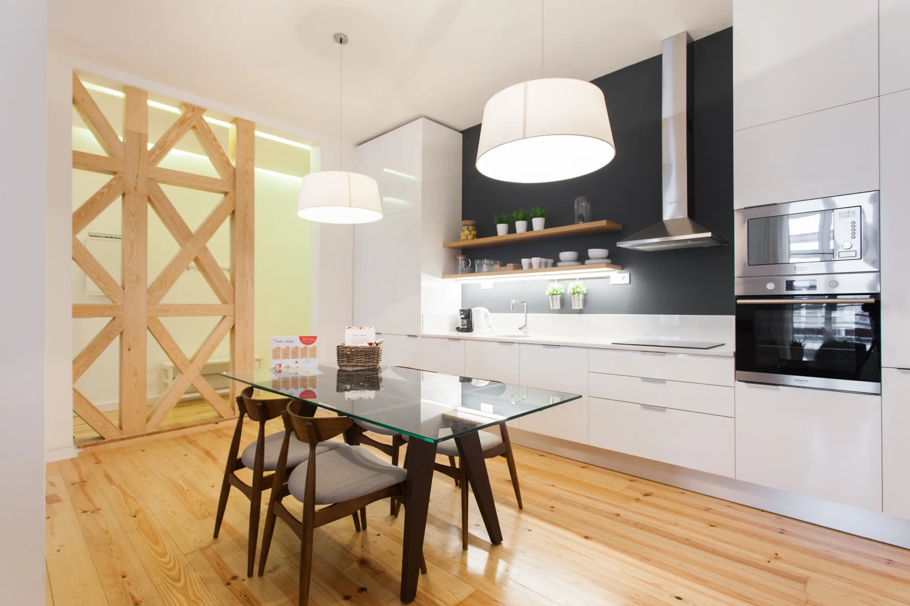 Una cocina luminosa con armarios blancos y una mesa de comedor de cristal.