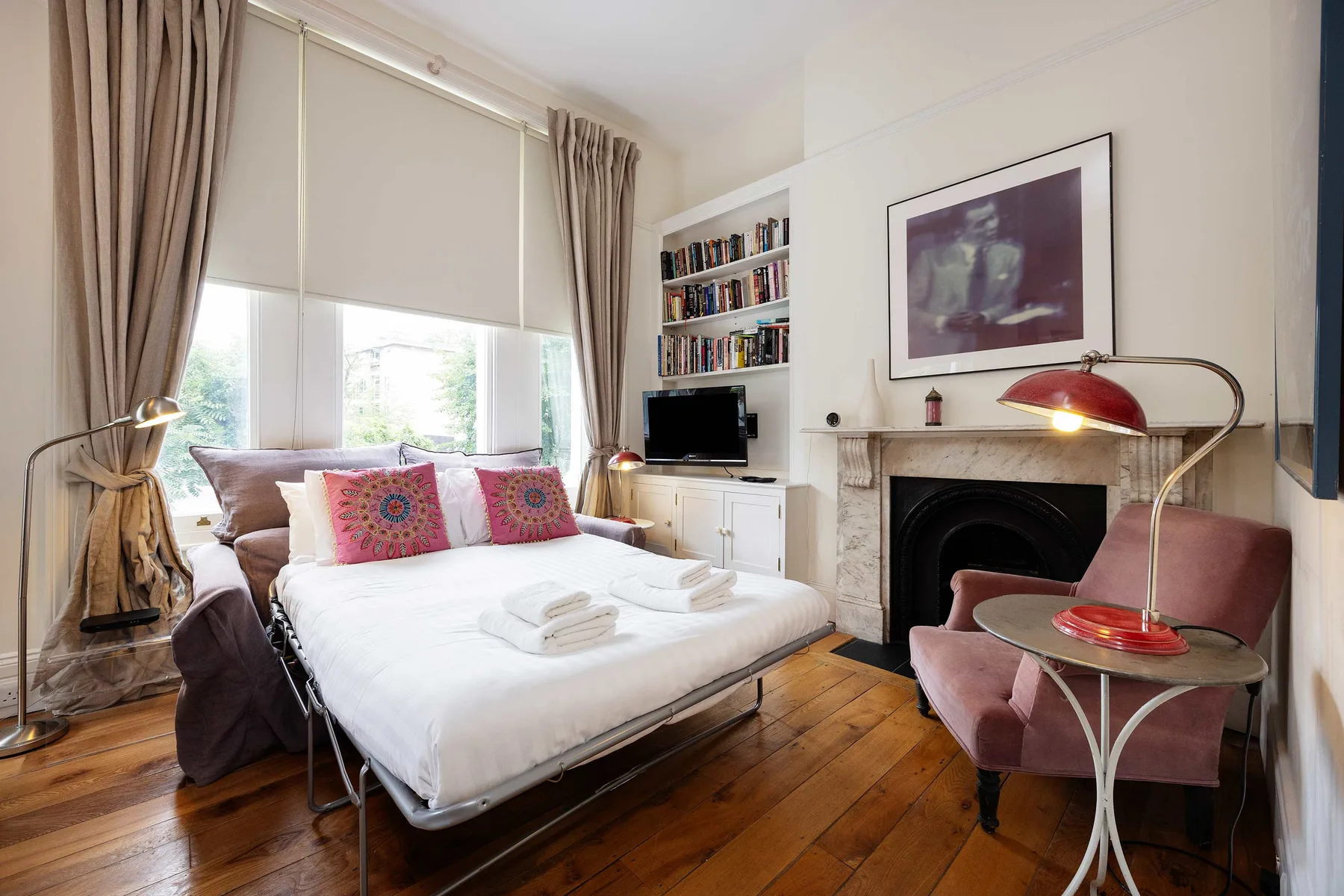 A bedroom with a bed, large windows, and a fireplace.