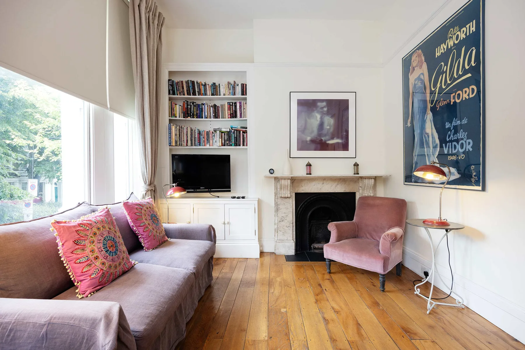 A living room with seating, a fireplace, bookshelves, and a large window.