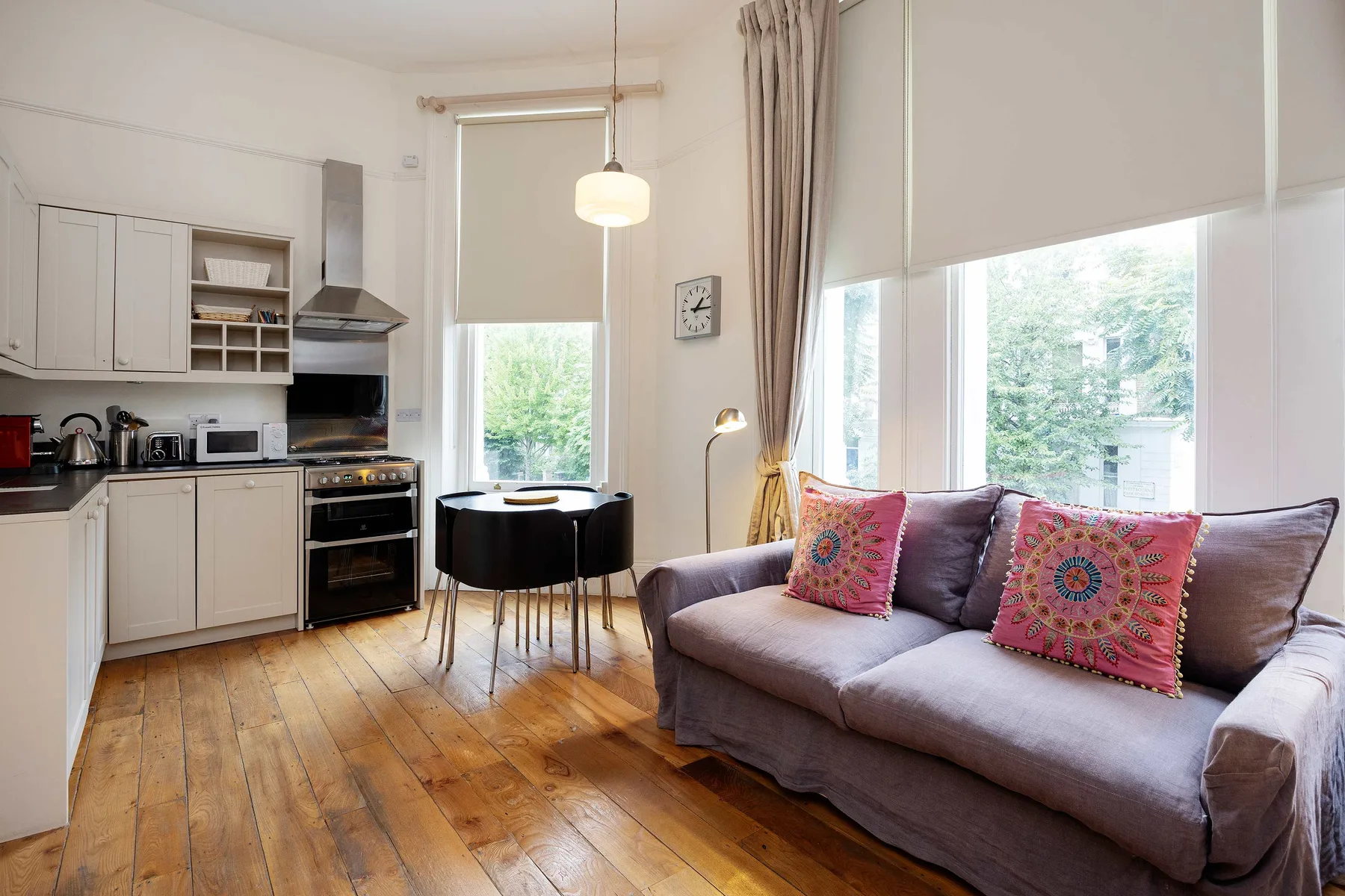 A bright living area with a sofa beside a compact kitchen and dining table.