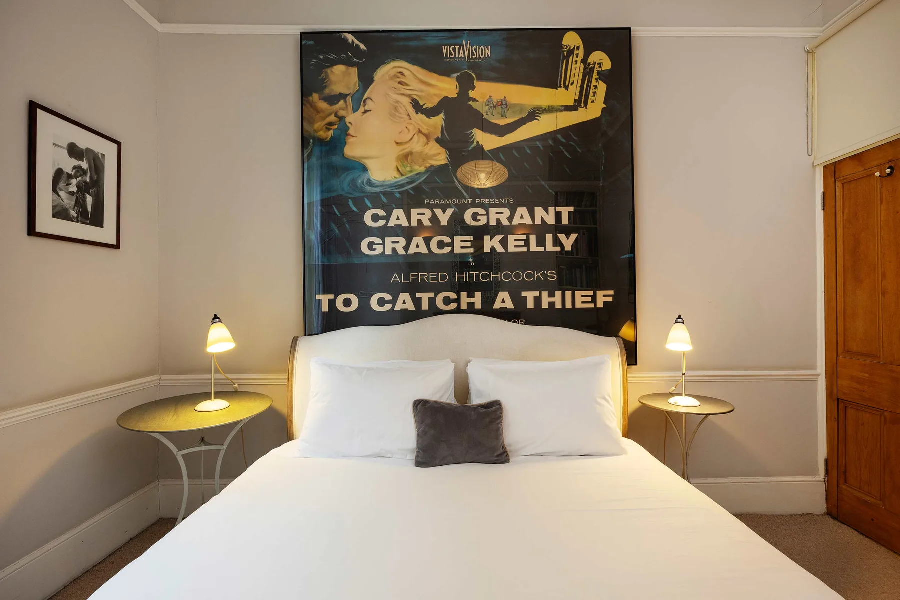 A bedroom with a neatly made bed beneath a large movie poster.