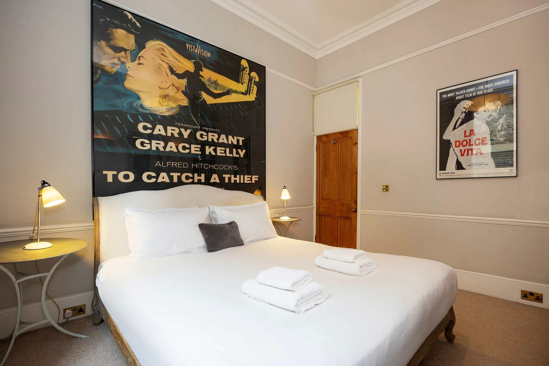 A bedroom with a neatly made bed and framed movie posters on the walls.
