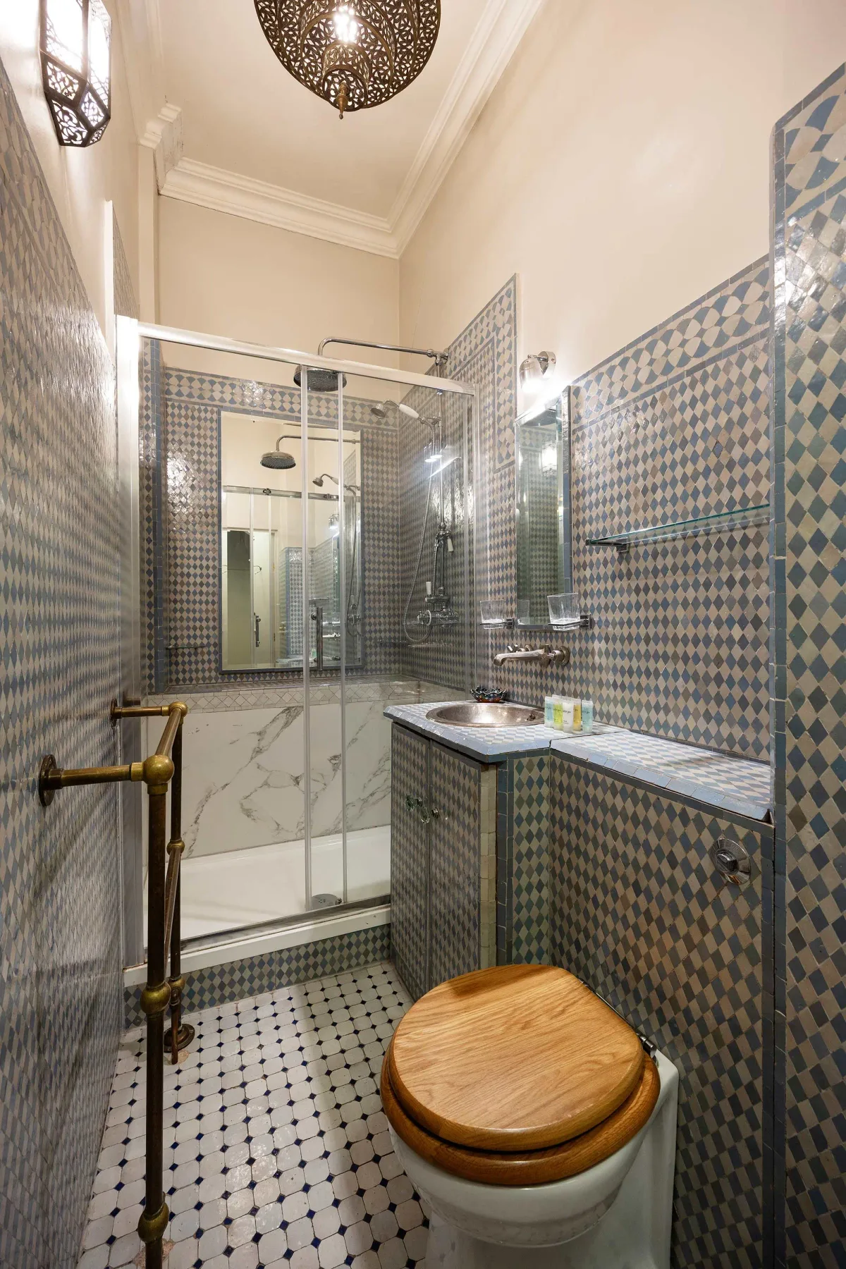 A tiled bathroom with a glass shower, sink, and toilet.