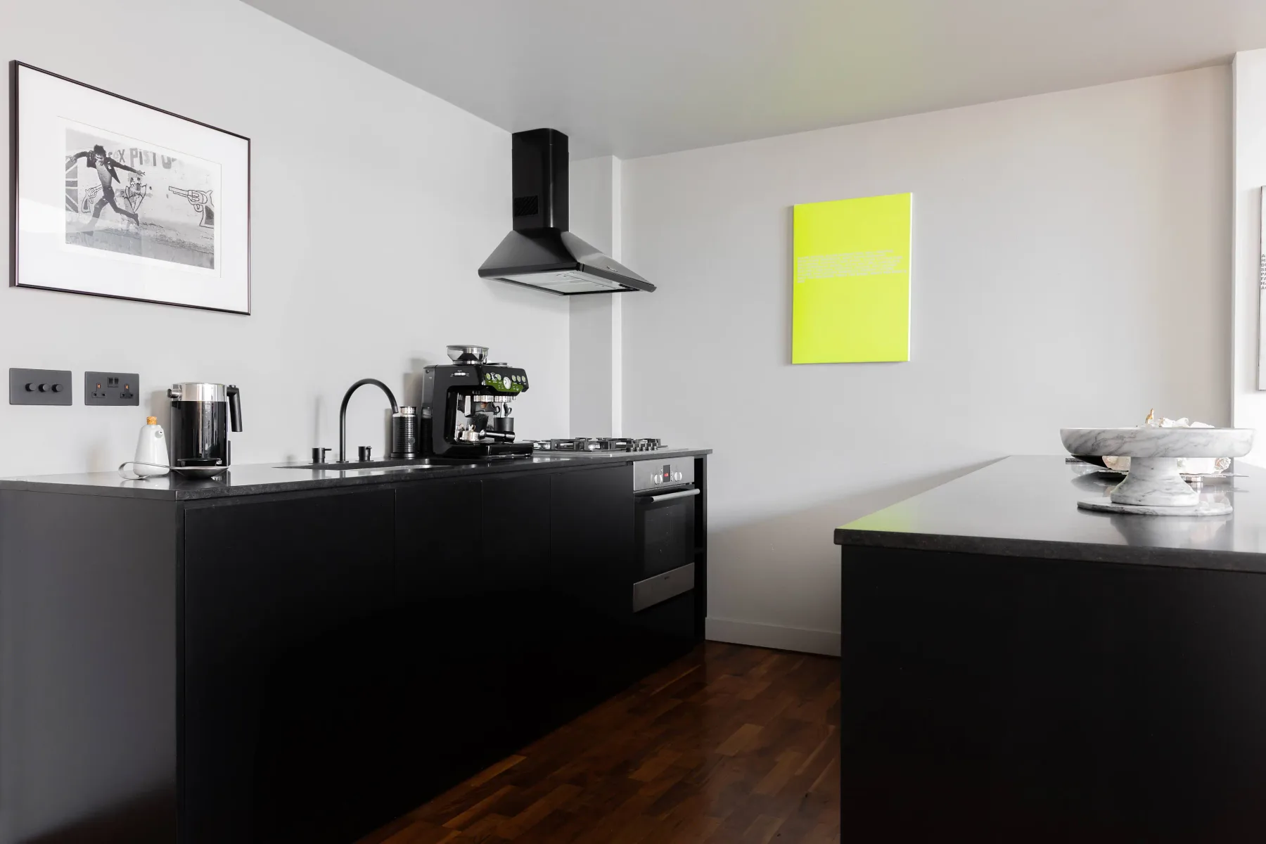 Una cocina moderna con gabinetes negros, electrodomésticos sobre la encimera y una isla central.