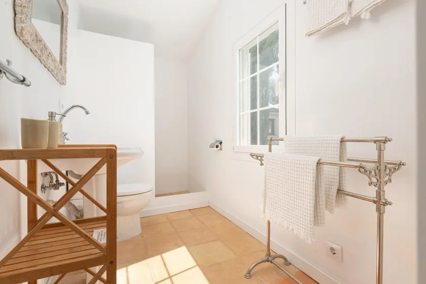 A bright bathroom with a bathtub, window, and towel rack.