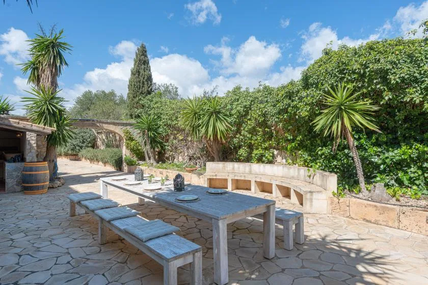 A stone-paved outdoor dining area with a long table and built-in seating.