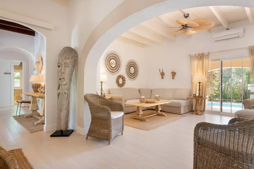 A bright living room with wicker seating, a sectional sofa, and sliding glass doors.