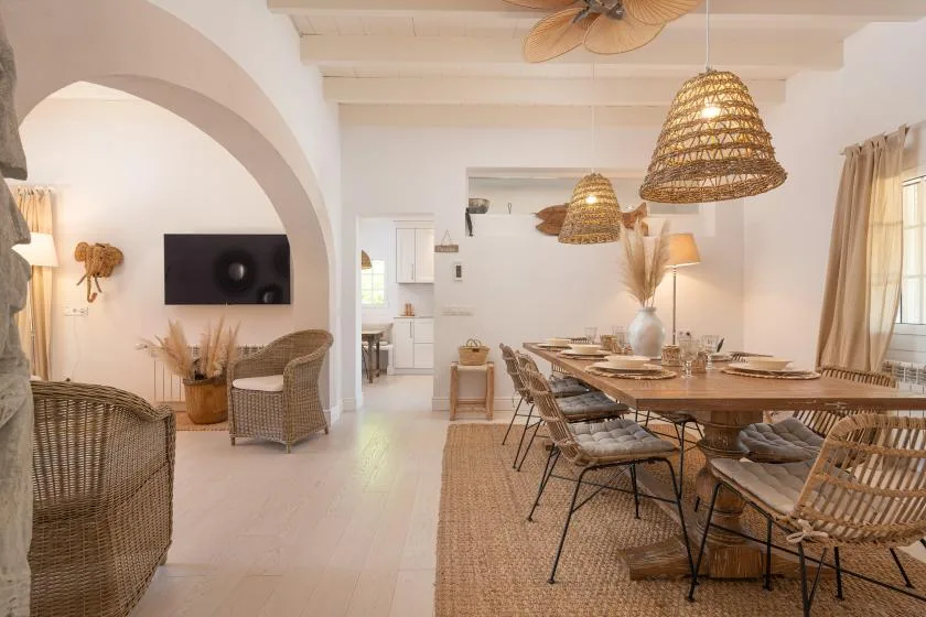 A bright dining area with a long table and woven pendant lights.