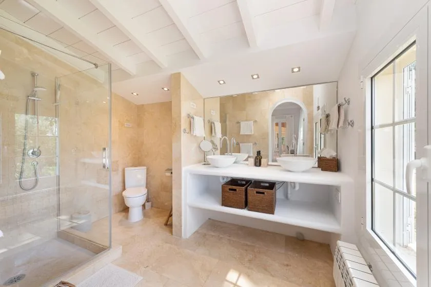 A bright bathroom with a glass shower and a double-sink vanity.