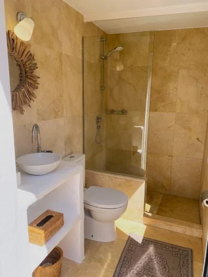 A tiled bathroom with a glass shower, toilet, and sink.