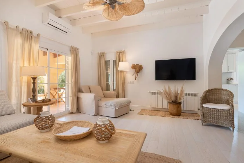 A bright living room with a television, seating, and large windows.