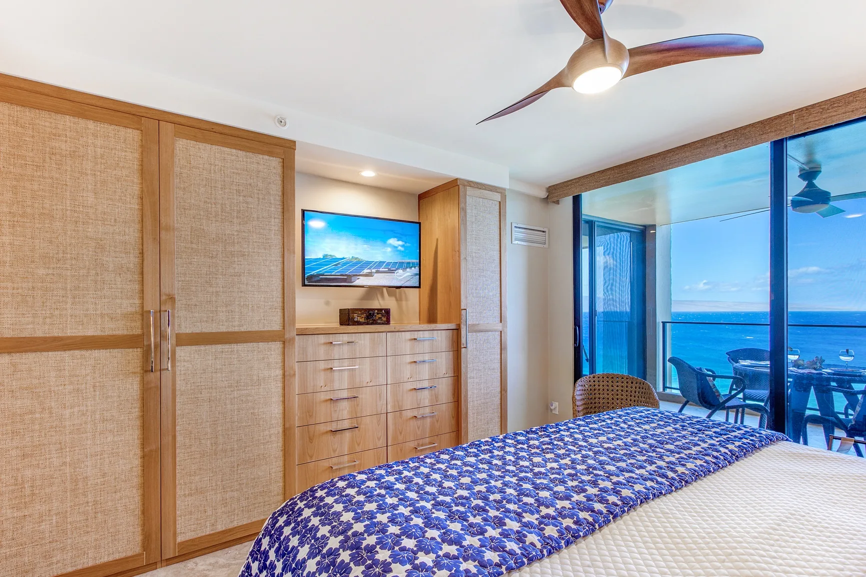 A bedroom with a bed, built-in storage, and large windows overlooking the ocean.