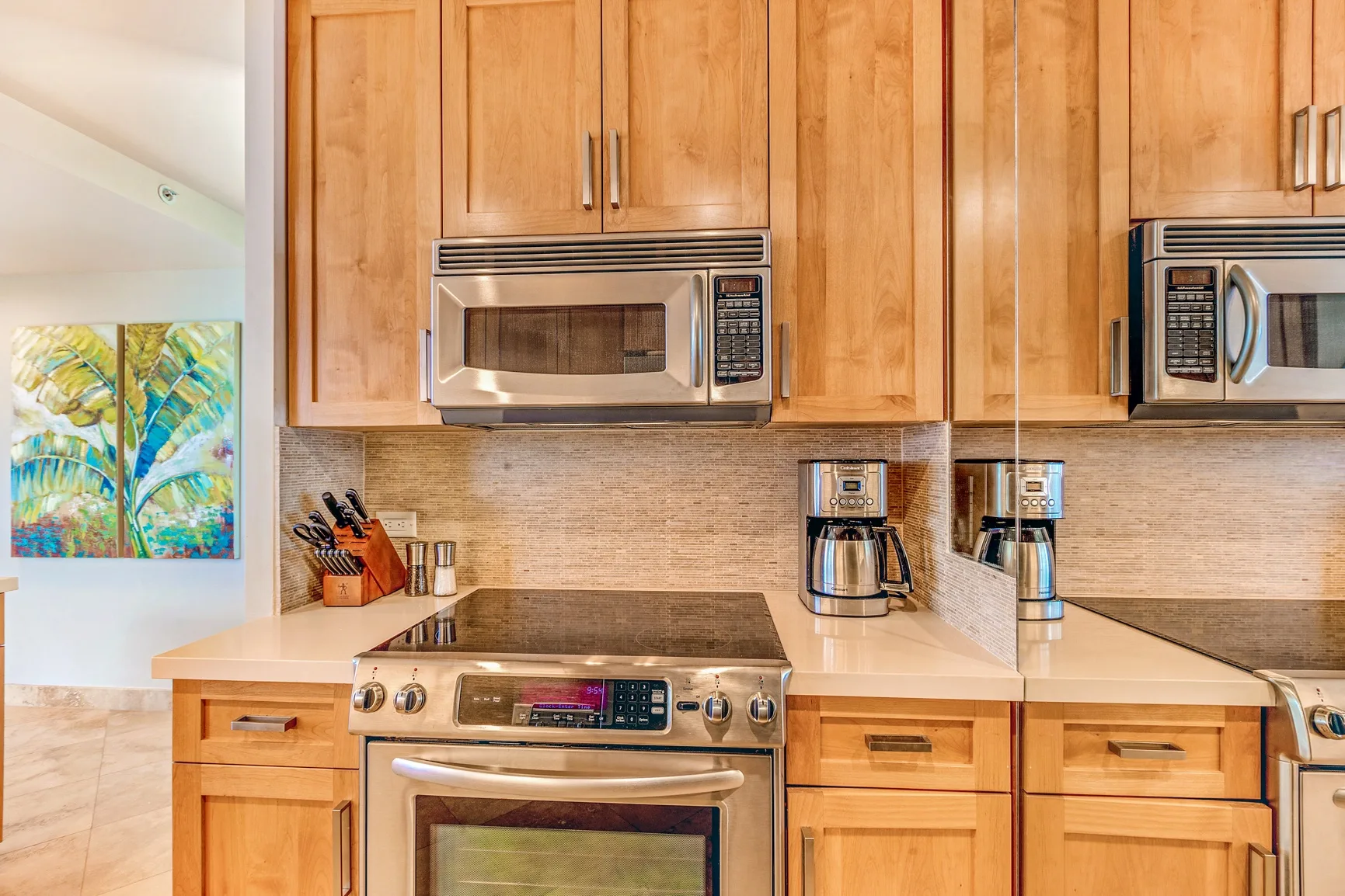 A kitchen with wooden cabinets, a microwave, and a stovetop.