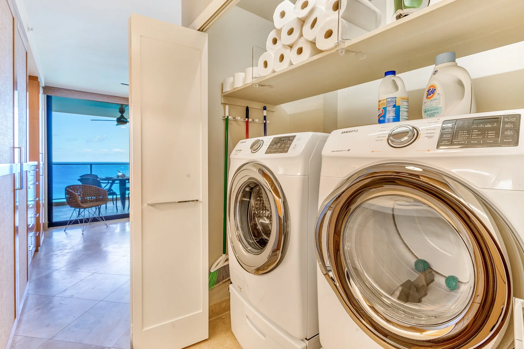 A laundry room with a washer and dryer beneath shelves of supplies.
