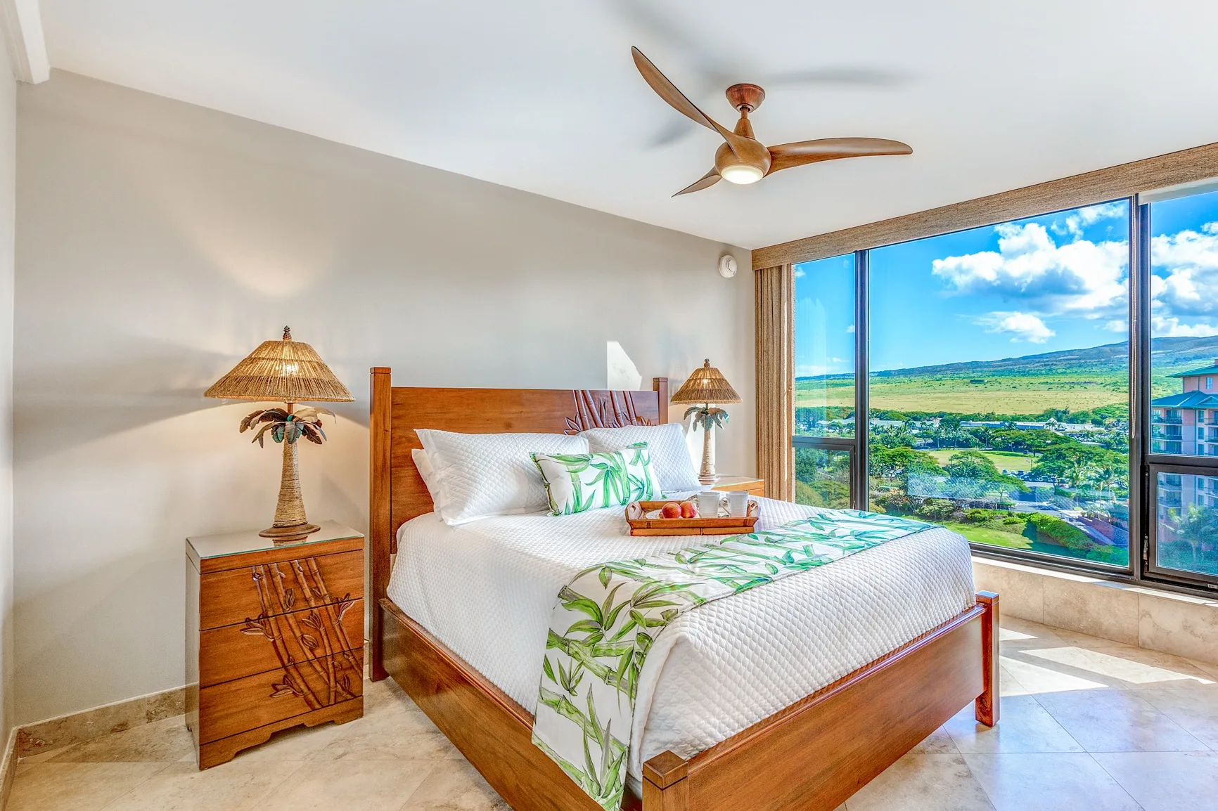 A bright bedroom with a wooden bed and large windows overlooking greenery.