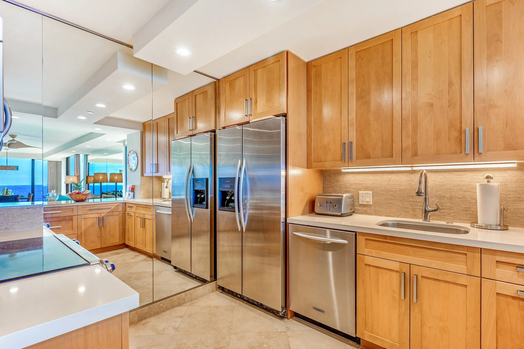 A bright kitchen with wood cabinetry, stainless steel appliances, and a sink.