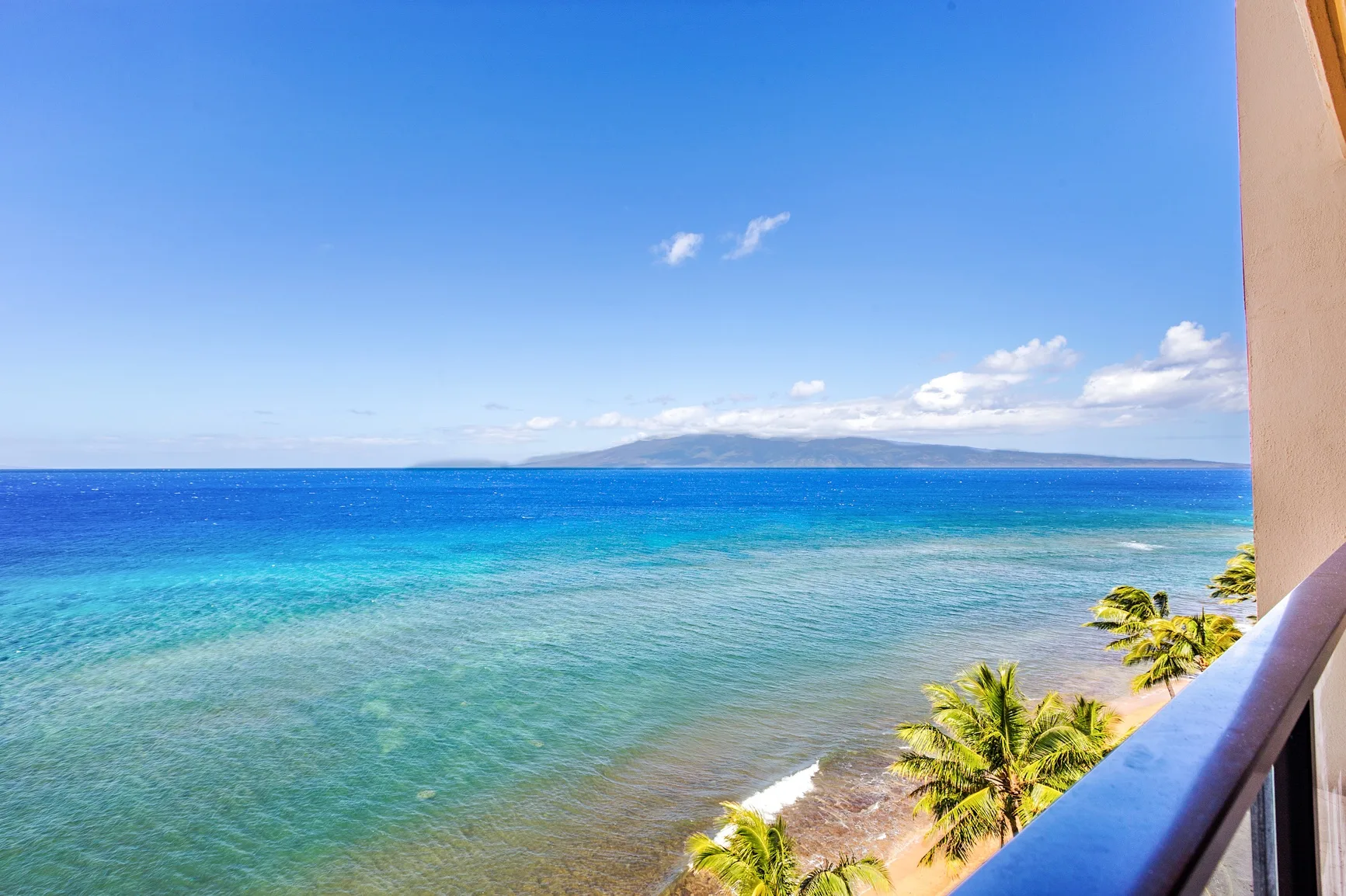 A tropical shoreline with turquoise water, palm trees, and distant hills.