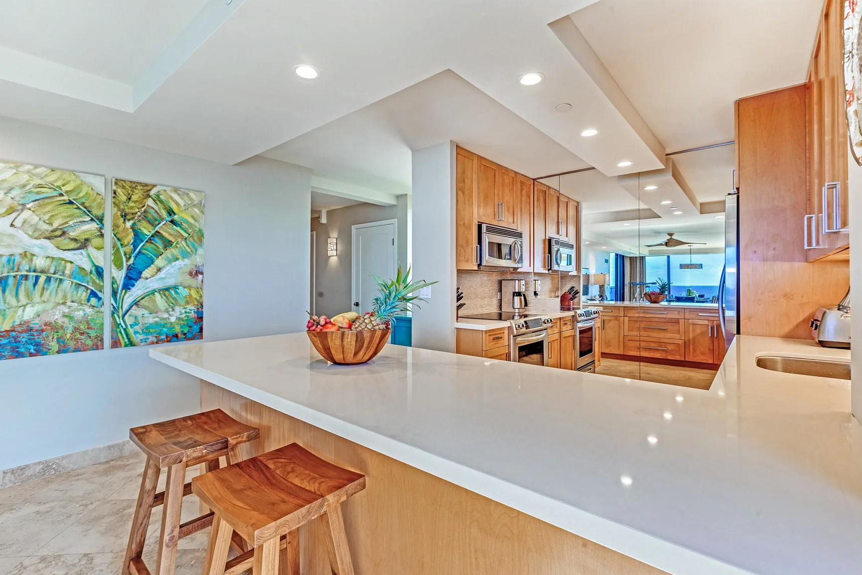 An open kitchen with wood cabinetry and a broad white island with seating.