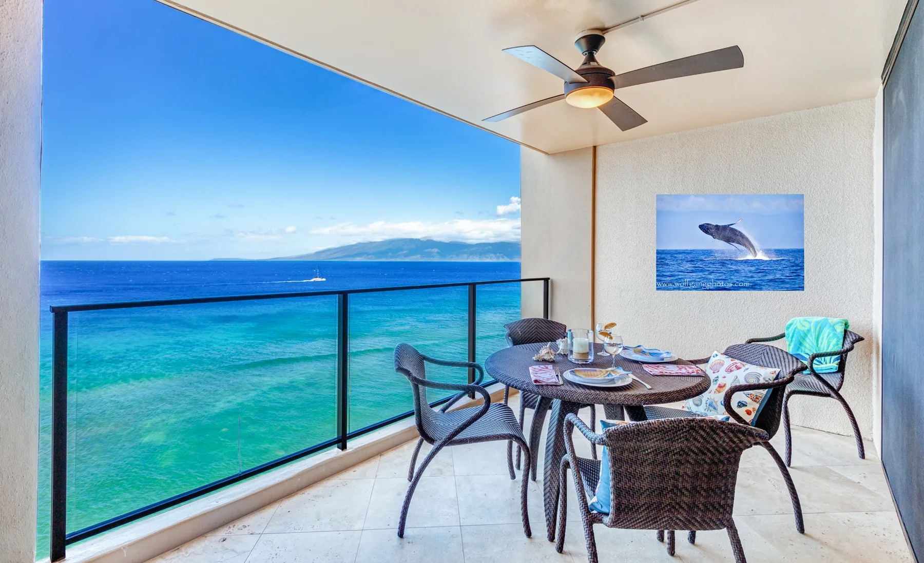 A covered oceanfront patio has a dining table and seating overlooking the water.