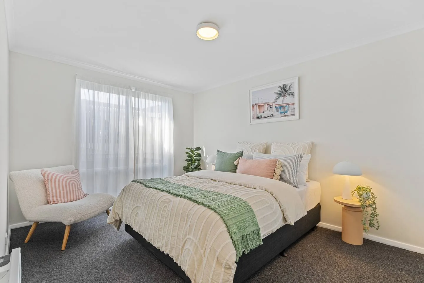A bedroom with a bed, an upholstered seat, and a curtained window.