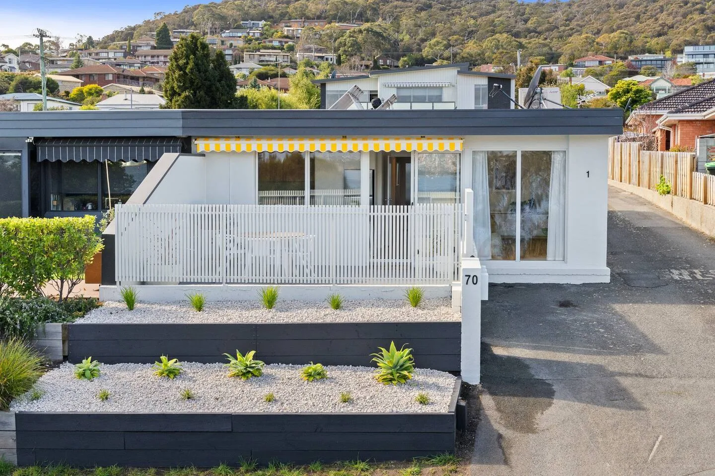 A modern single-story house faces a gravel garden and paved driveway.