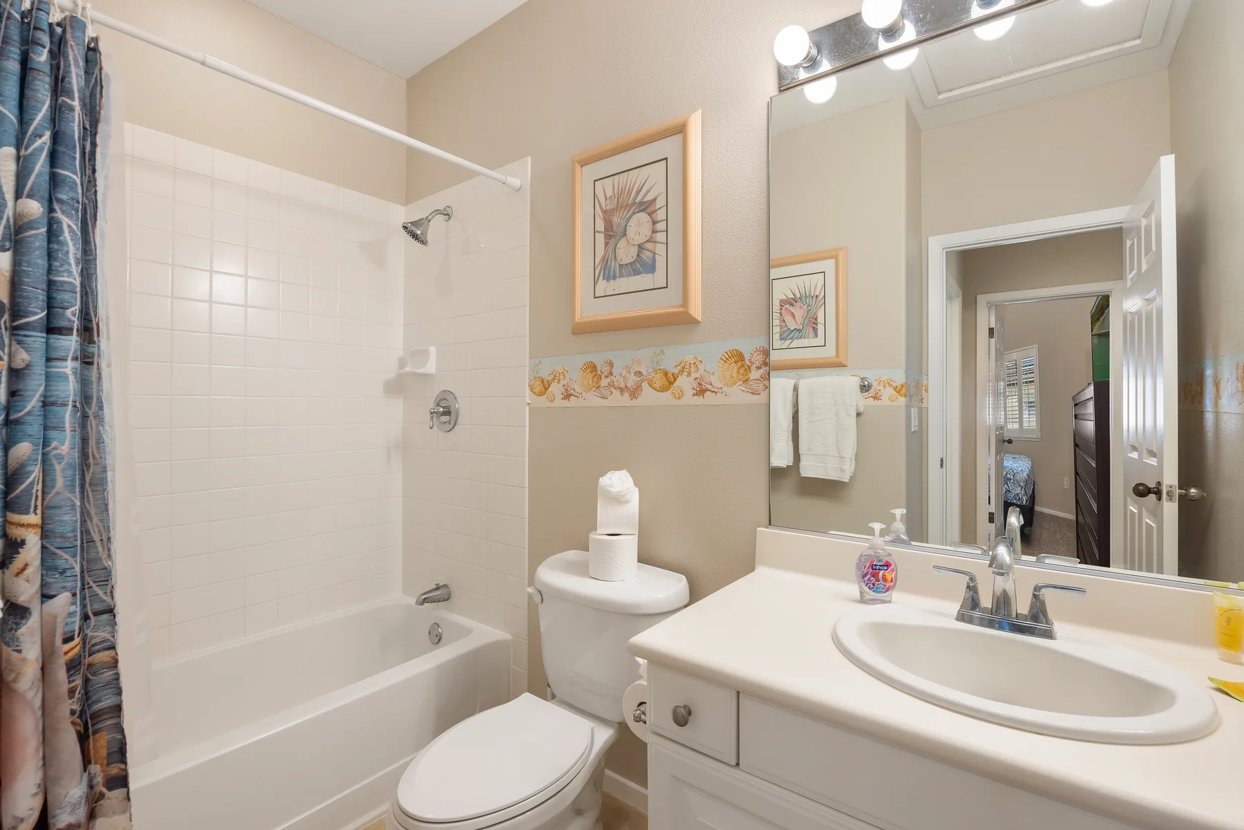Un baño con bañera, inodoro y lavabo bajo un espejo grande.