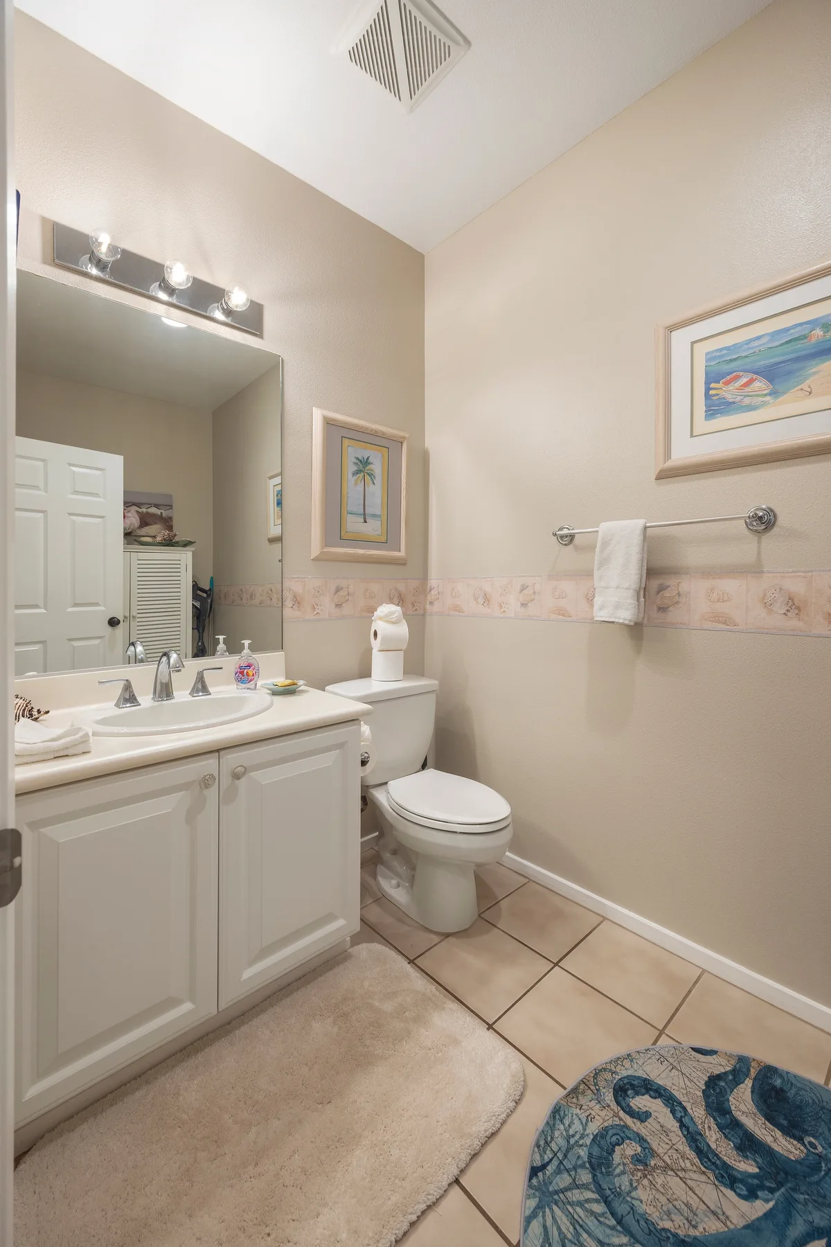Un lavabo y un inodoro están bajo un espejo grande, con toallas en la pared.